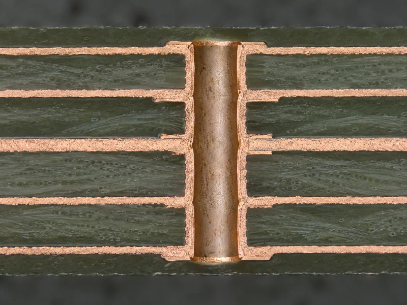 Polished multilayer PCB cross-section coupon under a microscope objective